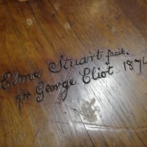Wood with the words Elma Stuart fecit for George Eliot 1874 carved into it.