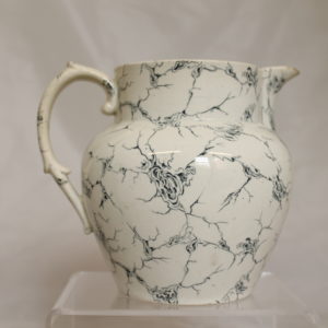 White jug with handle shown on the left hand side. There are blue lines across the surface.