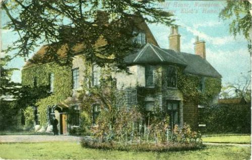 A colour postcard showing Griff House. A large house is shown. Ivy covers the walls. There is a garden in front of the house and a tree framing the house. A figure can be seen outside the front door. The words Griff House, Nuneaton. George Eliot's Home is written in the top right hand corner.