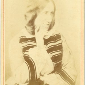 Black and white photograph showing George Eliot. She is turned slightly to one side and is resting her face lightly on her right hand. She is wearing a light coloured dress with dark stripes. The image has a red border and the words The Late George Eliot. Stereoscopic Co, Copyright are typed in red along the bottom.