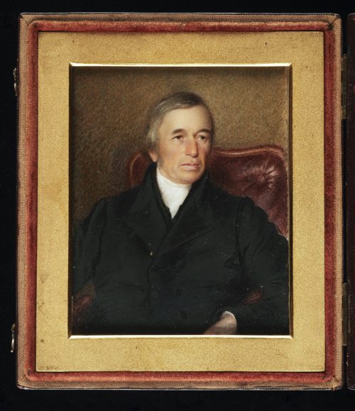 This is a miniature portrait painting inside a case, showing a man wearing a black coat and white cravat, seated with top portion of a red leather chair.