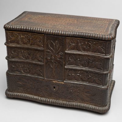Intricately carved wooden box. It has four tiers which are all decorated with a carved floral design. The bottom tier appears to have a very small key hole.